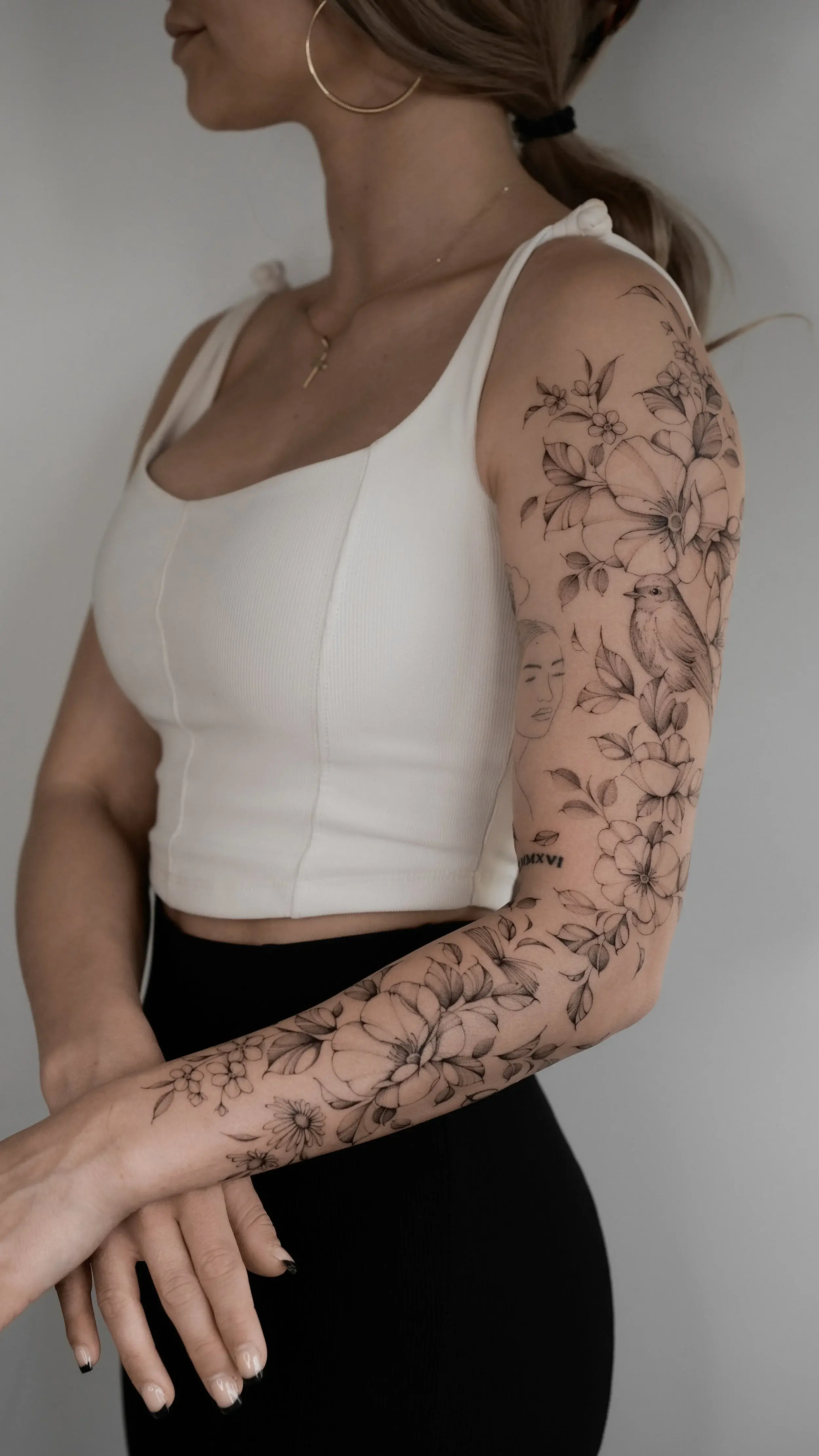 Frau mit botanischem Fine-Line-Arm-Tattoo
